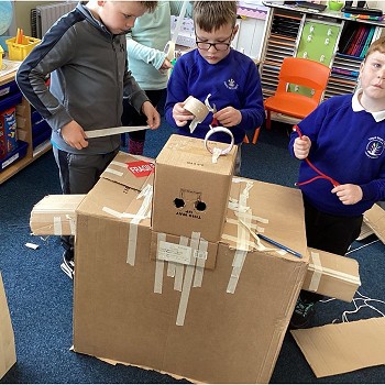 Children building a cardboard structure in a classroom