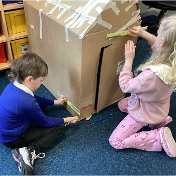 Kids measuring and decorating a cardboard model