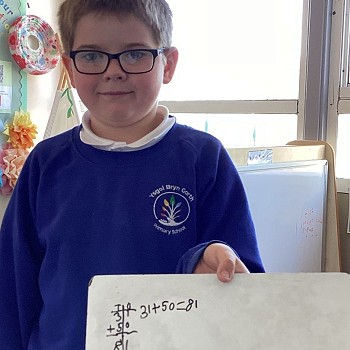 Student holding a whiteboard with maths work
