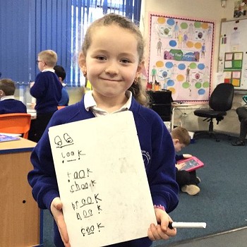 Student showing whiteboard with writing practice