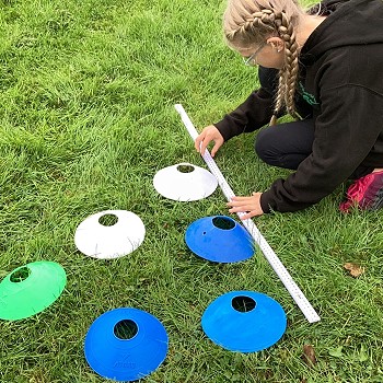 student using a large measuring stick on the grass