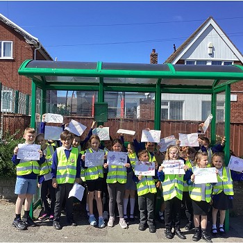 children wearing hi vis outside of a bus stop