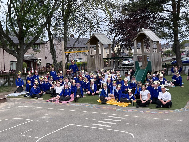 A group of children in the school playground sat on the ground